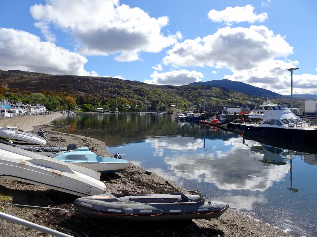 Harbour with boats beached on the left with reflection of clouds on water