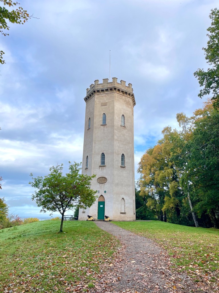 Large tower with green door next to trees 